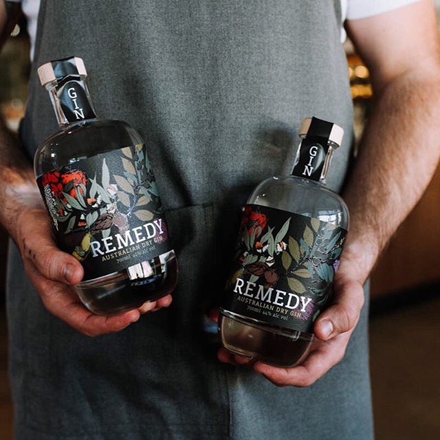 A man holding two bottles of Remedy Gin in each hand. 