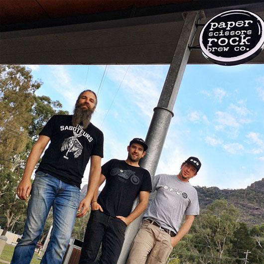 Three men standing in front of Paper Scissors Rock Brew Co.