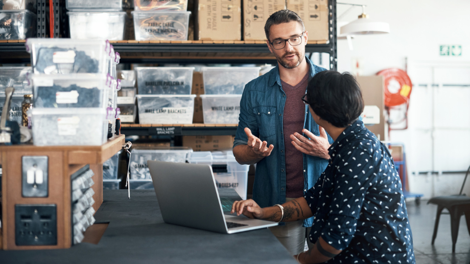 A man and woman talking in a storage warehouse.