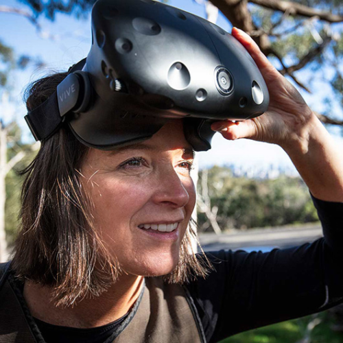Person outdoors using a virtual reality headset in a natural setting.
