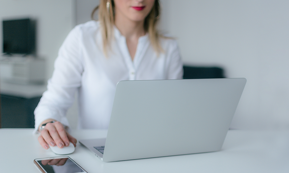 A women working on her laptop, holding a mouse