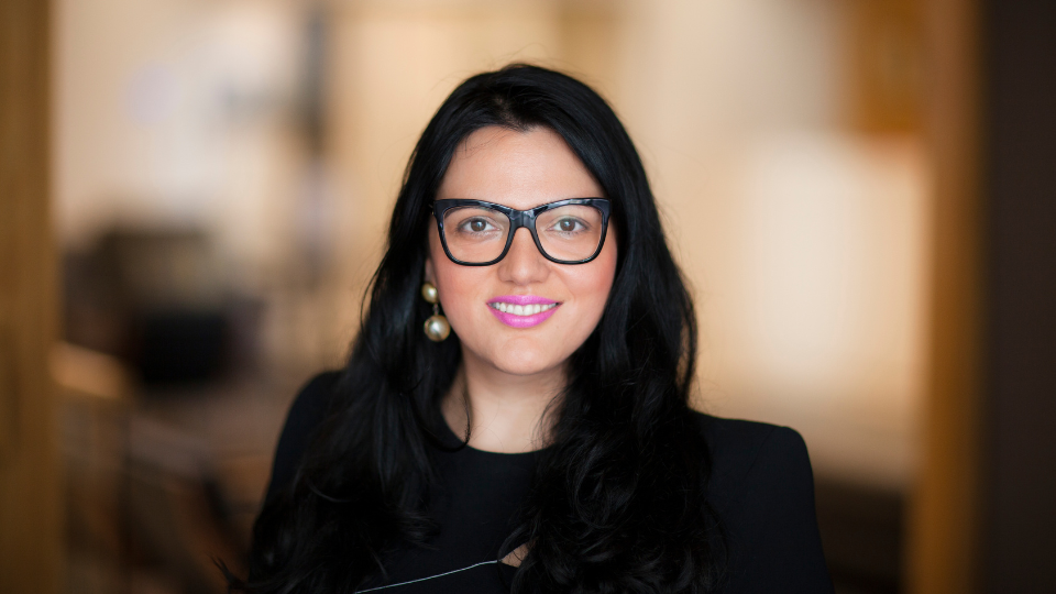 A woman wearing an orange jacket with Sheforce written on it.