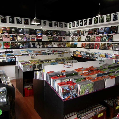 Hundreds of vinyl records of varying music genres are displayed on wall shelves and central display units in the Heartland Records store. 