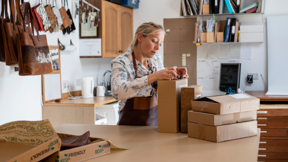 A woman adding a label to a cardboard package for delivery.