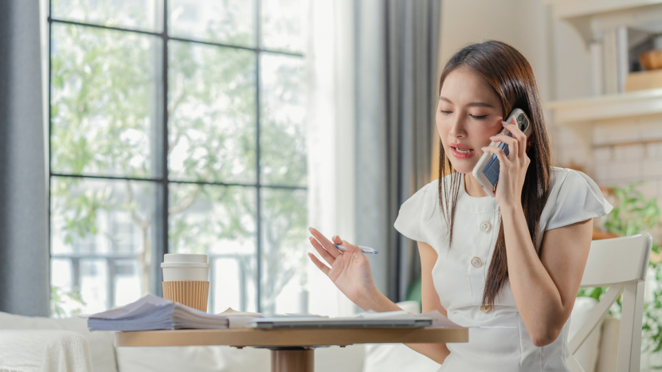 A woman on the phone, looking at papers in front of her.