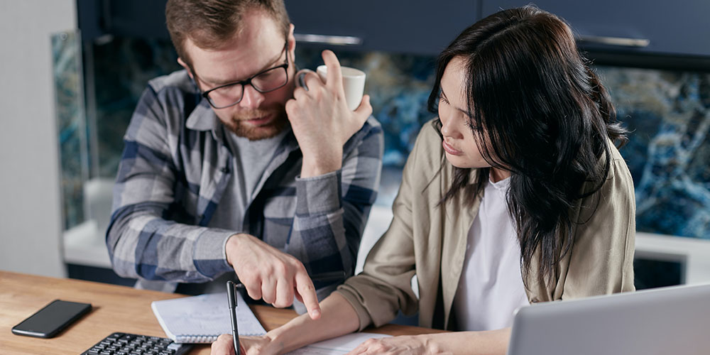 A young couple does their finances at the kitchen table.