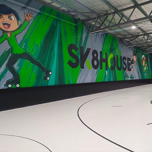 An indoor photo of Sk8house. A staking rink located in Carrum Downs, Victoria. There are cartoon drawings of people skating on the back wall.