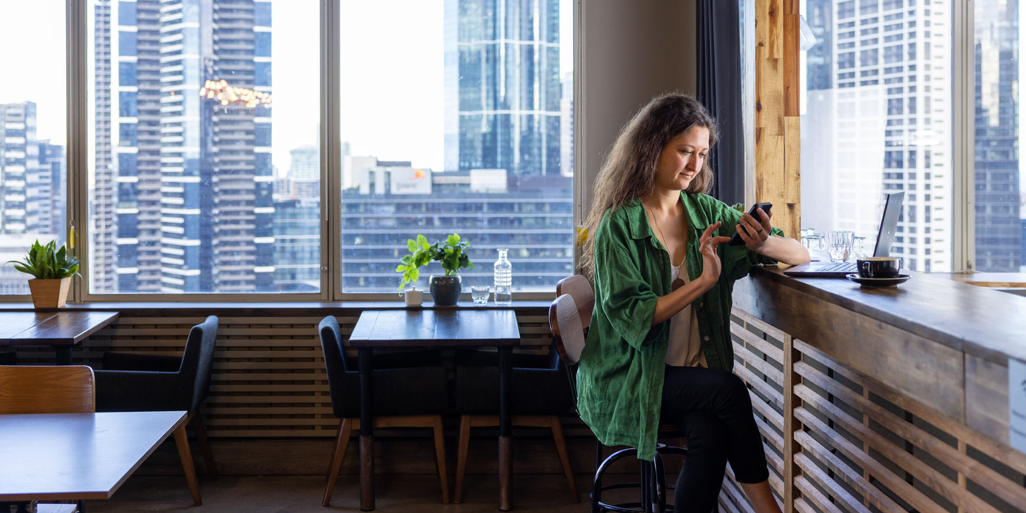 A young woman sitting on a stool looking at her smart phone