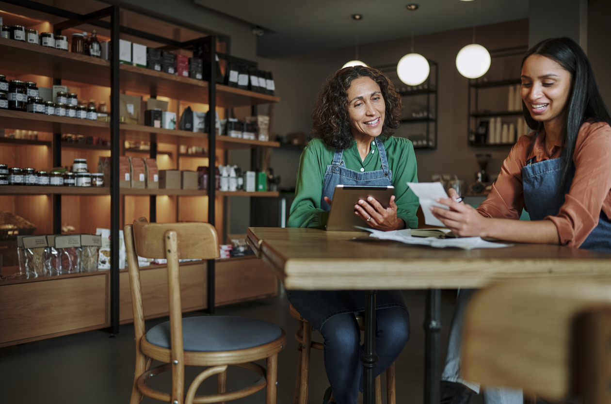 two women sitting at a table and looking at the computer