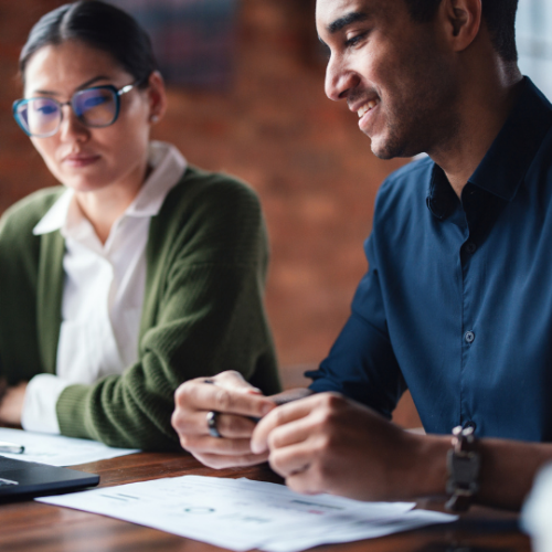 Two people reviewing documents and business plans together at a desk.
