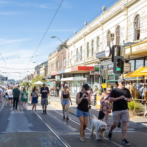 People walking and cycling through a busy shopping precinct.