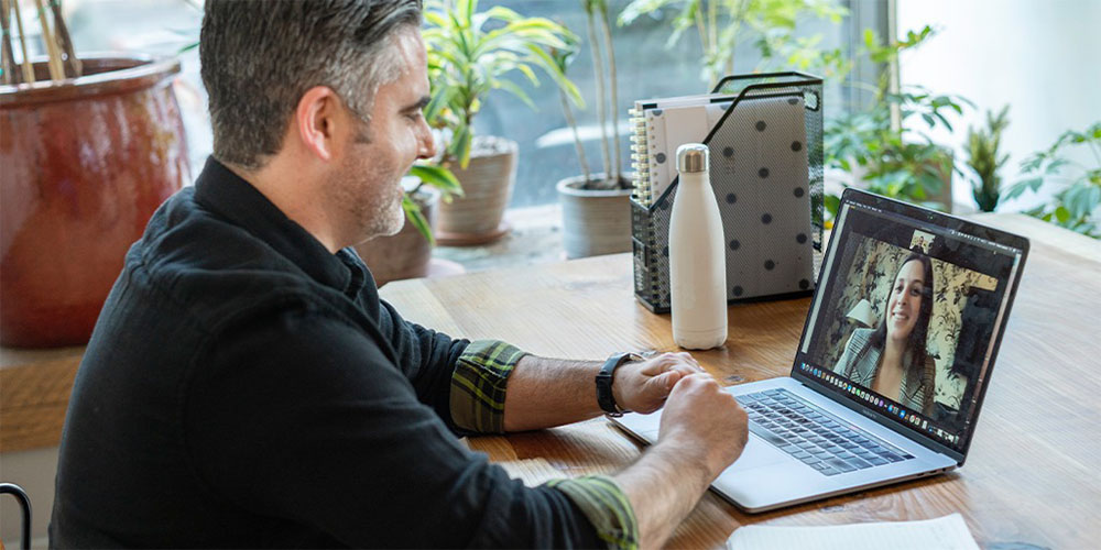 Man working from home, he is on a zoom call with a co-worker