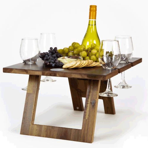 A gif of Indi Tribe Collective products. There are collapsible and portable wooden tables with wine glasses, wine bottles, crackers and cheeses on top.