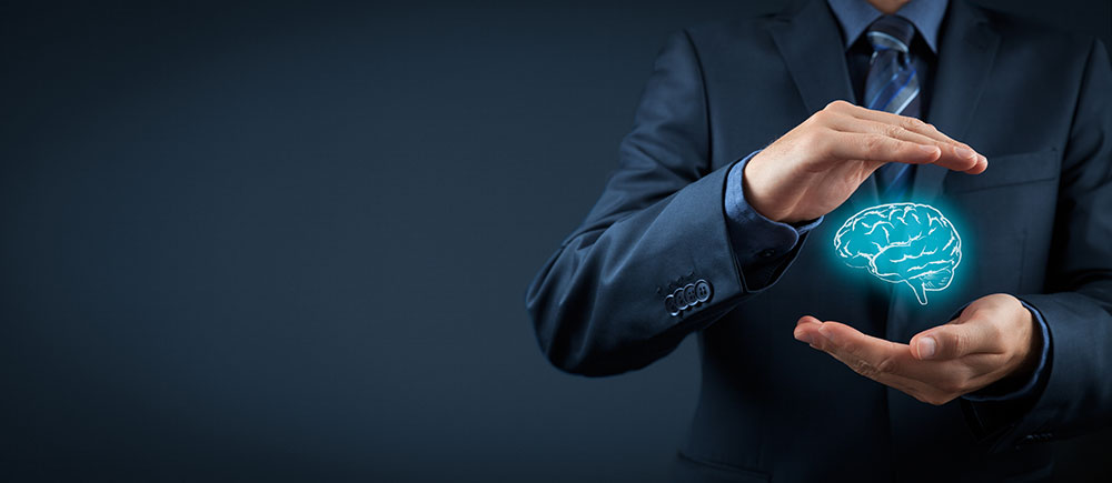 A man in a suit holds his hands in front of him, one above the other, a distance apart. Between them floats a glowing blue illustration of a brain.