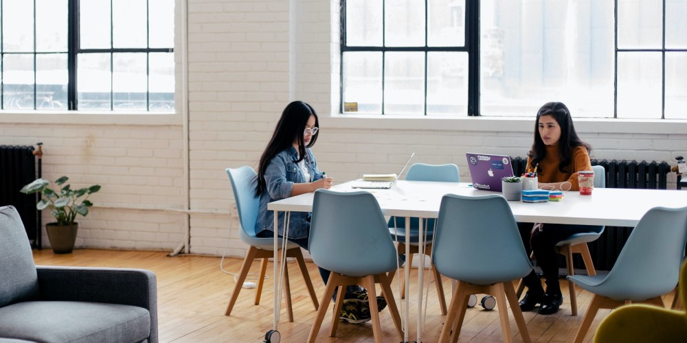 Two women working on laptops in a studio