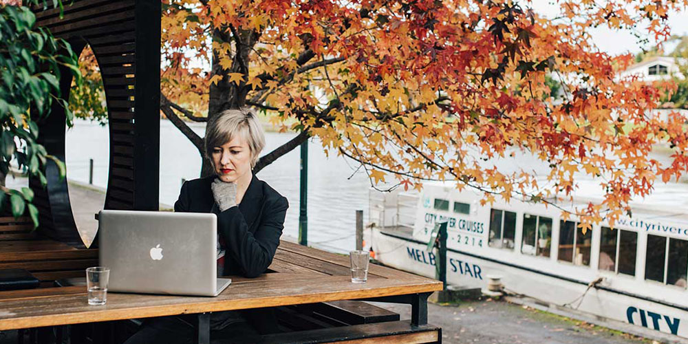 A woman works on her laptop at a café overlooking Melbourne’s Yarr river.