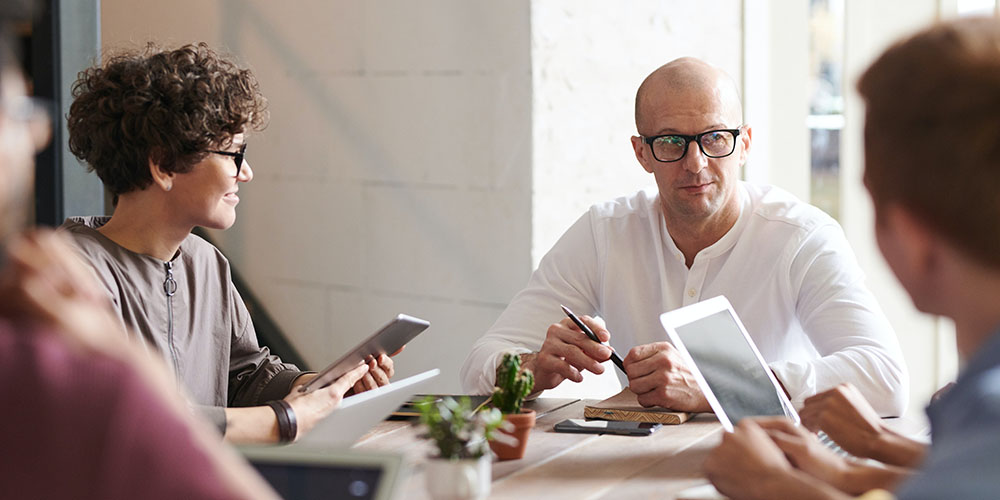 Coworkers with smart devices working around a table 