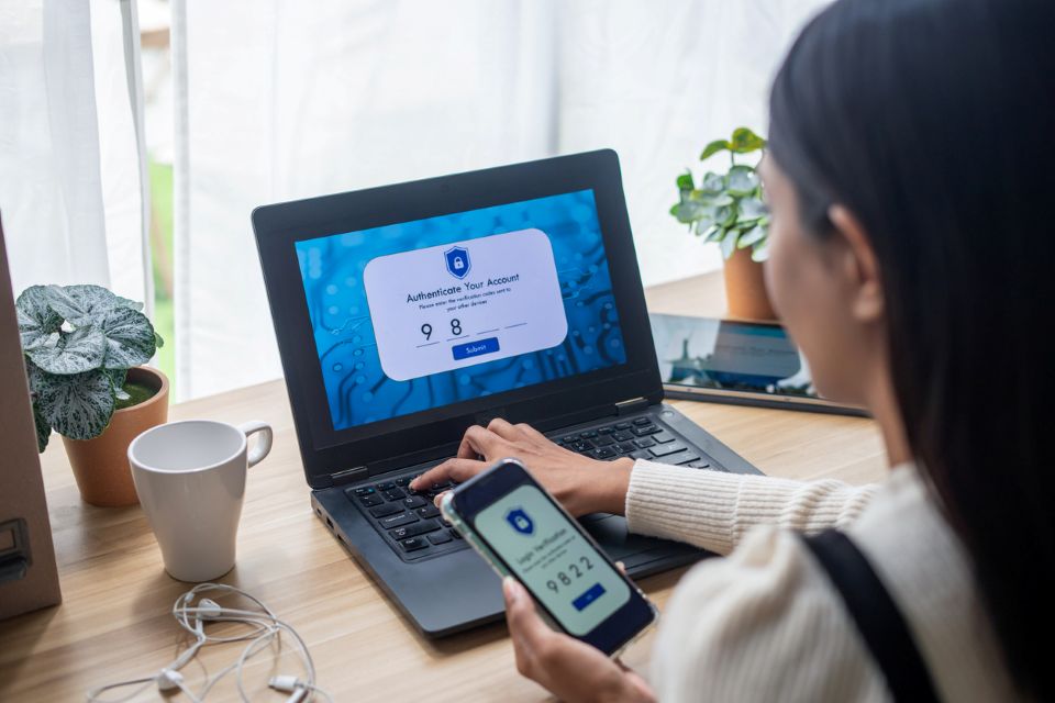 A girl with a kaptop entering a security code from her phone