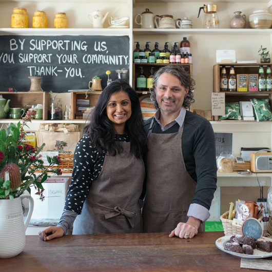 A man and a woman standing behind the counter at The Common Good store.