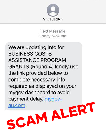 Image shows a screenshot of a scam SMS reading, "We are updating Info for BUSINESS COSTS ASSISTANCE PROGRAM GRANTS (Round 4) kindly use the link provided below to complete necessary Info required as displayed on your mygov dashboard to avoid payment delay: mygov-au.com"